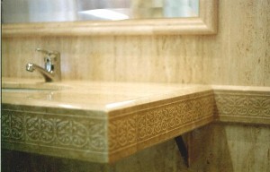 baño en marmol  travertino con cenefa grabada en faldon
